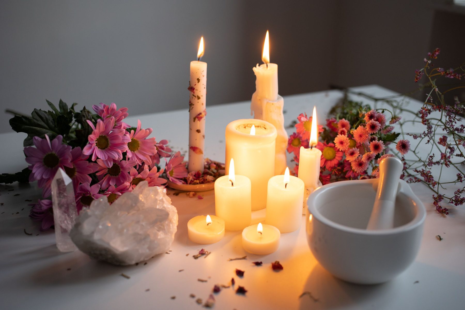 Candles, flowers and crystals arranged for a healing ritual