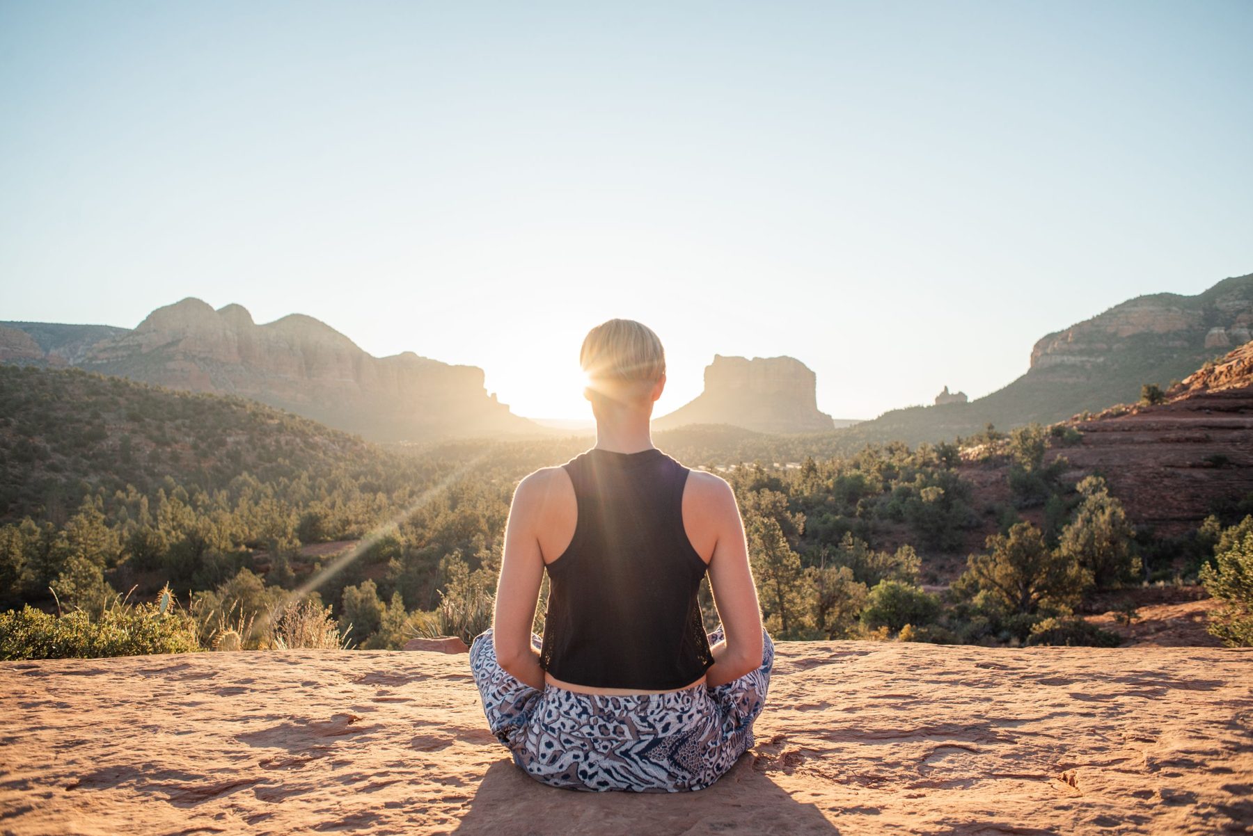 Person meditating at sunrise in the mountains
